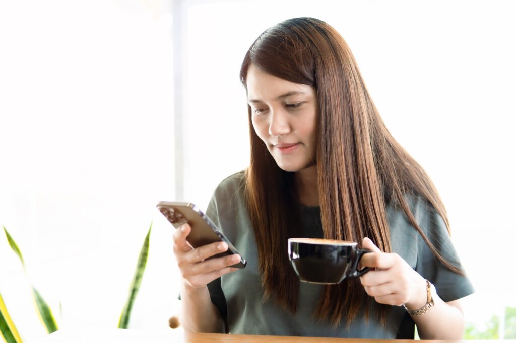 Asia women use smartphone and holding coffee cup in the cafe, lifestyle and online, social network.