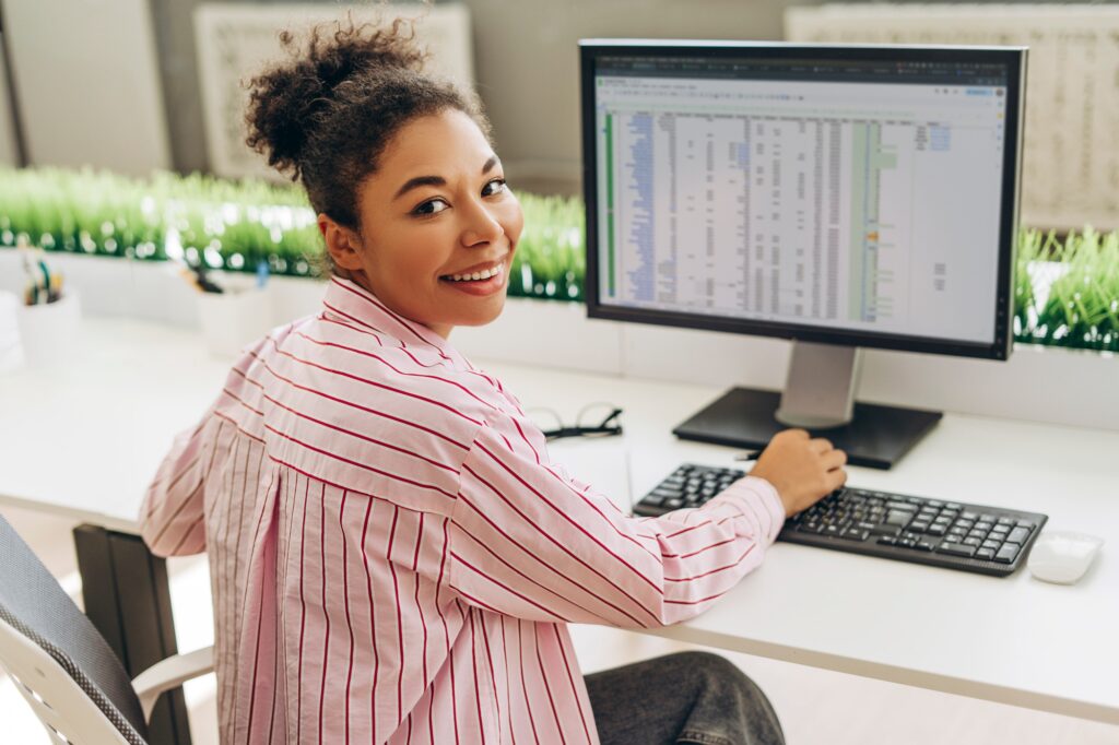 Smiling accountant working with spreadsheet software on desktop computer